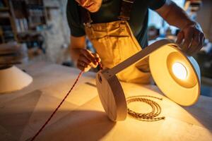 Artisan crafting custom lamp from blueprints. Maker selecting wires, refine design, check connection photo