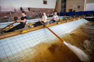 Rowing athletes skillfully manipulate oars, refining synchronization on rowing simulator in pool photo