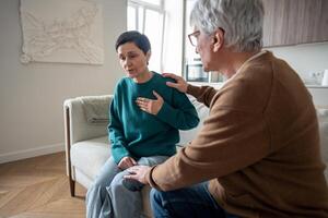 Heavily breathing woman grip chest on sofa, sudden panic attack while husband unsure how to help photo