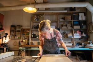 Woman carpenter inspecting wooden beam straightness with ruler before cutting with saw in workshop photo