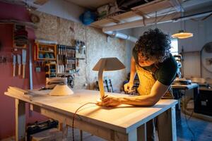 Skilled woodworker examining handmade lamp detail. Checking red wire connection, custom design diy photo