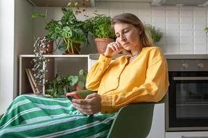 Restless woman browsing phone feed checking updates during downtime at home among house plants photo