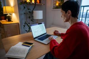 Mature woman tracking stock exchange graphs and cryptocurrency rates via app on laptop, investments photo