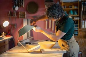 Artisan check lamp dimensions of curved plywood shade with caliper. Woodworker creating custom lamp photo