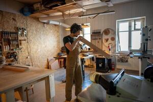 Professional meticulous carpenter inspecting wooden beam quality before workshop processing photo