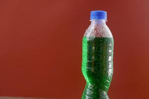Green soft drink bottle red background photo