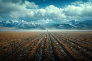 Tranquil Agricultural Landscape with Tractor on Snow-Capped Mountain Horizon photo