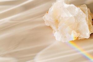 Quartz clear stone with Rainbow Beam at sunlight, bright sun glare and flare, beige blur background. Shiny magic crystal make caustic and light effects at sunshine, harmony and beauty of nature. photo