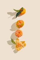 Fresh juicy orange yellow tangerines as minimal flat lay, Sweet Citrus fruits with green leaves on beige background. Top view of still life layout of mandarin oranges, above frame, copy space photo
