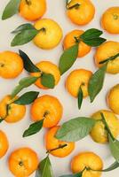 Top view juicy orange yellow tangerines with green leaf, Natural citrus fruit pattern minimal style, light beige background. Organic, healthy, vegetarian and plant-based food concept, pastel tones photo
