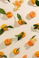Fresh juicy orange yellow tangerines as minimal flat lay pattern, Sweet Citrus fruits with green leaves on beige table background. Still life geometric pattern of mandarin oranges overhead, above photo