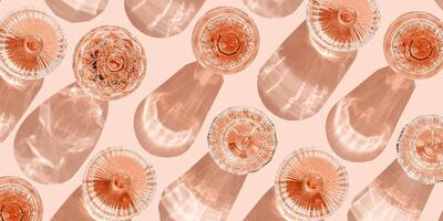 Minimal summer party banner, glasses of rose wine or champagne on pink with shadows and light reflections. Bright shine wineglass with sparkling alcohol drink at sunlight, top view monochrome pattern photo