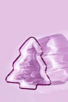 Purple colored glass plate as New Year tree, Christmas fir at sunlight with shadow and sun flare on lilac. Winter holiday concept, minimal trend abstract aesthetic monochrome vertical photo