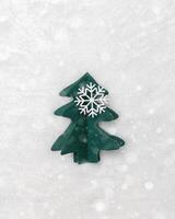 Christmas tree paper cutting, winter holiday background, snowing. Handmade green fir decorated snowflakes on white fur. Aesthetic top view, minimal flat lay trend, Happy holidays mood photo