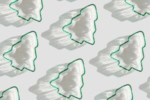 Minimal pattern Green color glass form as New Year trees, Christmas fir at sunlight with beautiful shadows and sparkling sun glare on white background. Winter holiday concept, aesthetic trends photo