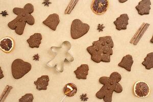 Christmas gingerbread cookies, biscuits, candies and cookie cutter on beige baking paper. Top view minimal pattern, aesthetic flat lay from holiday sweet food, traditional bakery, new year photo