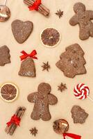 Christmas gingerbread cookies or biscuits on baking paper, winter seasonal traditional bakery with spices, dry orange, cinnamon sticks, anis, candy. Top view sweet food pattern, new year flat lay photo
