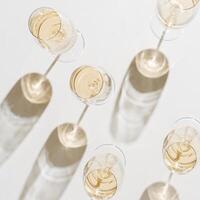Set of glasses of white wine at wine tasting, Minimal trend concept. Top view shiny wineglass standing on table at sunlight, shadow and sun flare, alcohol drinks on white grey background, copyspace photo