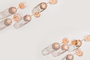 Rose wine glasses Minimal style above view. Holiday aesthetic still life photo, top view wineglass at natural light, sun shadows, beige pink pastel color, drink banner background, copyspace photo