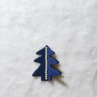 Minimal xmas card with blue Christmas tree cut of craft paper on white fur, happy holidays concept. Diy blue tree fir decorated round pearl beads. Minimal above view, copy space for greetings photo