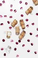 Champagne corks and sparkling confetti, top view composition, holidays, celebration concept. Wooden cork and muselet on pastel background at sunlight shadows. Flat lay festive minimal trend pattern photo