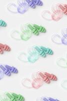 Reusable silicone colorful earplugs, for swim, sleep, rest as minimal trend pattern on white background. Soft, flexible ear plug on cord against noise, protect hear, top view, flat lay photo