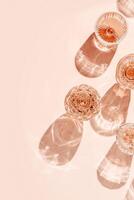 Minimal composition Top view glasses of rose wine or champagne on pink background, artistic shadows and sun flare. Aesthetic still life crystal wineglass, sparkling drinks for summer party, copyspace photo