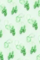 Reusable silicone green earplugs, for swim, sleep, rest as minimal trend pattern on light green background. Soft, flexible ear plug on cord against noise, protect hear, top view, flat lay photo
