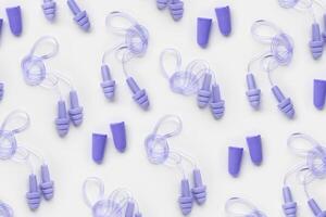 Colored earplugs as minimal trend pattern, reusable silicone and rubber ear plug on cord against noise, protect hear, for swim, sleep, rest. Creative aesthetic flat lay, above view, pastel tones photo