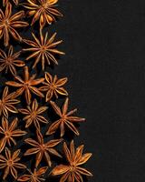 Anise stars food background, top view close up photography fragrant spices dry anise seeds on black background, natural organic seasoning texture, dark colored minimal flat lay, copy space photo