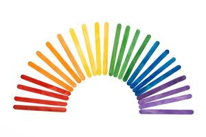 Rainbow color wooden ice cream sticks on white. Colorful abstract arch photo
