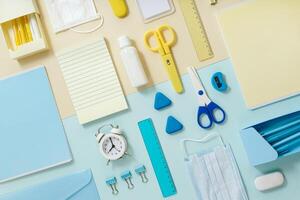 Flat lay with stationery for study and work, face mask and sanitizer Back to school concept. photo