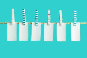 White pieces of paper hang on clothespins on rope, empty space for letters or text. Summer concept photo