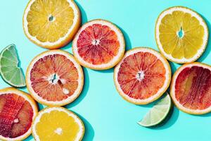Composition with slices citrus fruits, grapefruit, red orange, lemon, lime on turquoise. Summer food flat lay photo