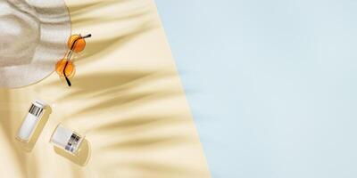 Summer beach rest concept background with sun hat, colored sunglasses, plastic bottle cream with palm tree shadows. photo