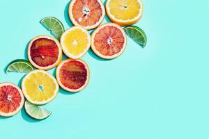 Bright slices citrus fruits, grapefruit, red orange, lemon, lime on pastel turquoise background. photo