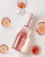 Many glasses of rose wine and bottle sparkling pink wine top view. Light alcohol drink for party. photo