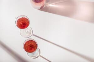 Two glasses of rose wine or champagne sweet and dry, shadows from sun. Light alcohol sparkling drink for party. photo