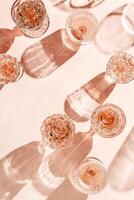 Summer flat lay of rose wine crystal glasses casting shadows on peach background. Minimal layout sparkling alcohol drinking, champagne drinks at sunlight, wine aesthetic party concept, copyspace photo