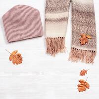Autumn comfortable clothes and decorative yellow leaves. Scarf and cap for woman photo