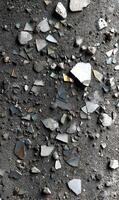 Debris of shattered glass on rough dark surface creating abstract patterns reflecting ambient light with rugged texture photo