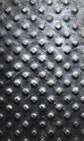 Textured metal surface with raised circular and square elements creating a tactile and visually interesting pattern with industrial feel photo