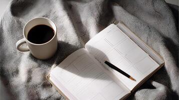 Cozy morning scene featuring an open notebook with a pen and a cup of black coffee on a soft blanket photo
