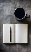 Open notebook with pen and coffee mug on textured gray background evokes creativity and reflection inspiring focus and writing photo
