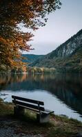 A serene autumn day at a tranquil lake with a wooden bench perfect for peaceful contemplation and reflection in nature photo