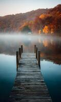 Scenic autumn lake view with wooden pier leading to misty waters and colorful foliage landscape serenity photo