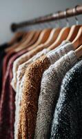 Warm and cozy sweaters hanging neatly on a wooden rack creating a fashionable winter wardrobe collection display photo