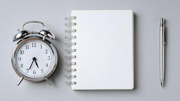 A minimalist workspace featuring an alarm clock notebook and pen perfect for time management notes photo
