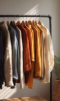 Assortment of colorful sweaters and shirts hanging on a rack promoting minimalist wardrobe style and organization in natural light photo