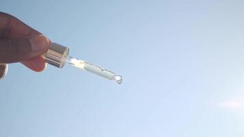 Holding a dropper with liquid under clear sky video